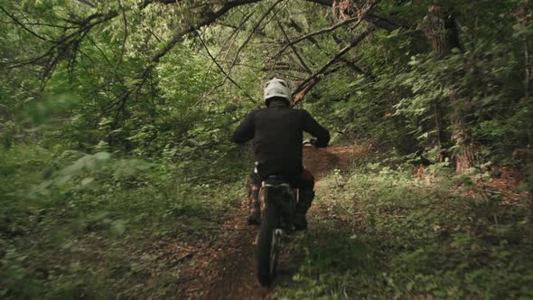 Slowmo of Man in Helmet Riding Motorcycle in Forest