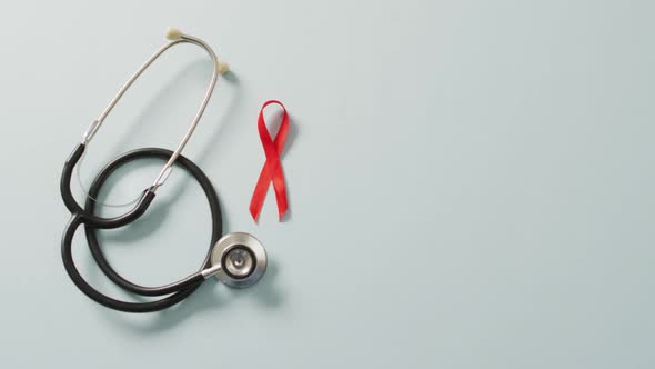 Video of stethoscope and red blood cancer ribbon on pale blue background