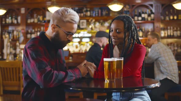 Portrait of Romantic Diverse Couple Holding Hands on Date in Pub