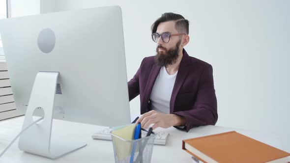 Concept of Office Work or Freelancing. Young Bearded Stylish Man Working at the Computer in the