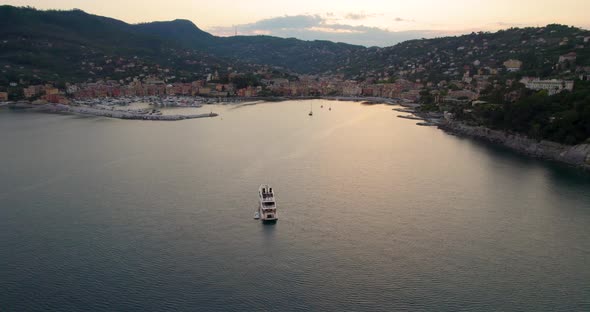 Yacht floats just outside harbor of tourist resort, Liguaria; sunset aerial