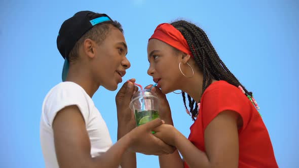 Multi-Ethnic Couple in Love Drinking Glass of Fresh Cocktail Through Two Straws