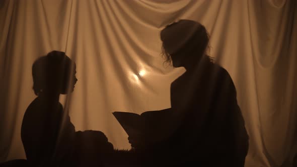 Silhouettes of Woman and Boy Reading a Book of Fairy Tales