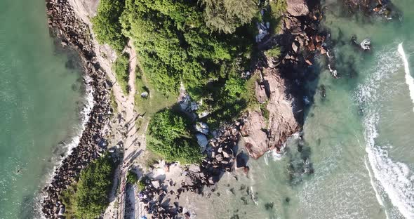 Aerial footage of the the beautifu rocks and sunny beach of Armação in Florianópolis, Brazil.