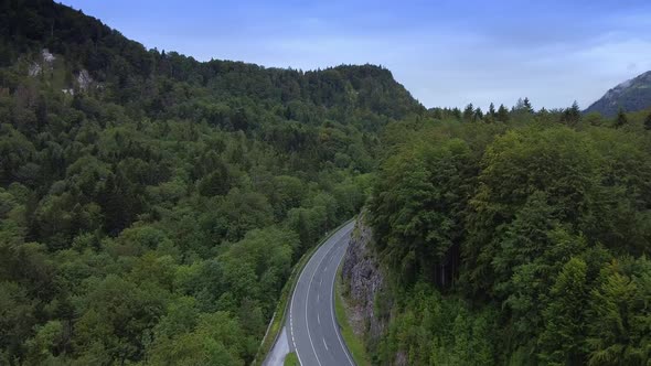 Aerial View of Asphalt Road Between Mountains Covered with Green Forest