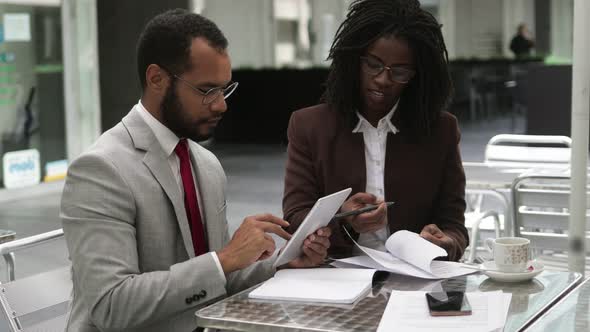 Two Business People Signing Documents at Cafe