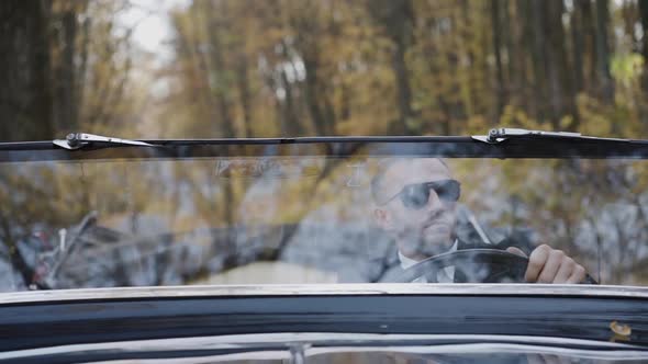 Portrait Through Windscreen of Rich Man in Sunglasses Sitting at Handlebar