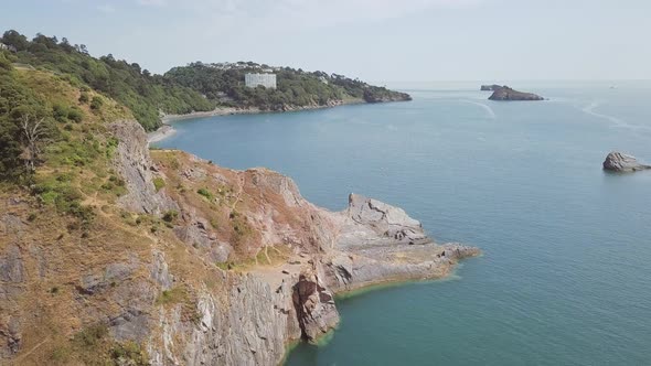 Drone ascending over the cliffs of Torquay in England. There are some smaller rock formations in the