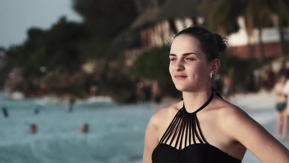 Young Beautiful Woman Stands on Exotic Beach and Looks Into the Distance Sunset