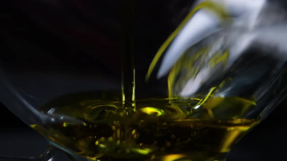 Empty Transparent Glass Jar with Golden Oil Pouring Inside in Slow Motion with Bubbles