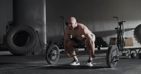 Athletic Man Doing Clean and Jerk Exercise Barbell in Gym