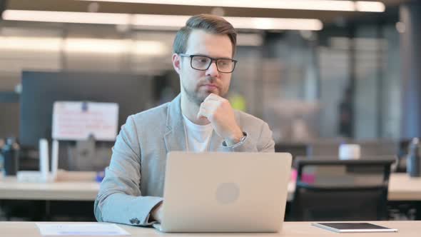 Casual Man with Laptop Thinking in Office