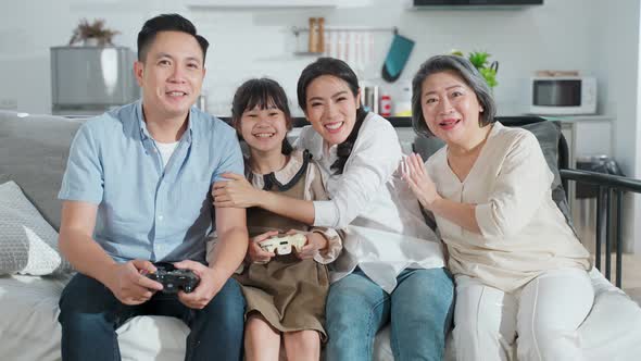 Asian happy family, parent playing console game with young children together in living room at home.