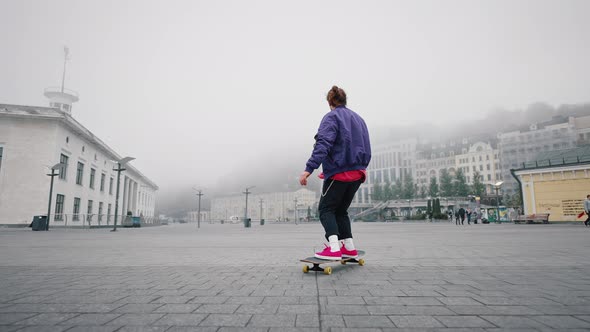 Skater Performing with Longboard at Foggy Morning in Urban City Square