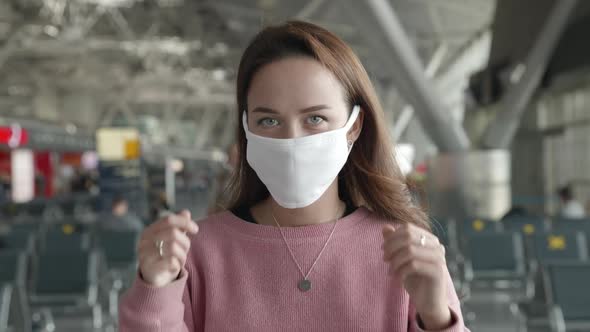 Portrait of Woman Put Off Medical Mask Looking Straight at Camera in Airport Terminal