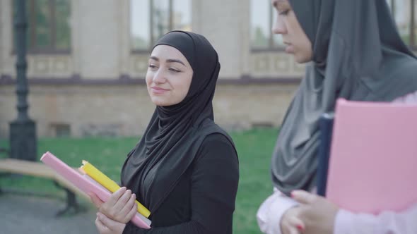 Side View of Confident Muslim Students Strolling at University Yard and Talking. Two Positive