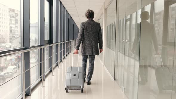 Old Hipster Man in Grey Suit with Suitcae Going Along the Airport Hall