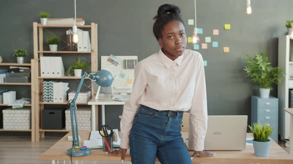 Portrait of Young Afro-American Woman Standing in Office and Looking at Camera with Serious Face