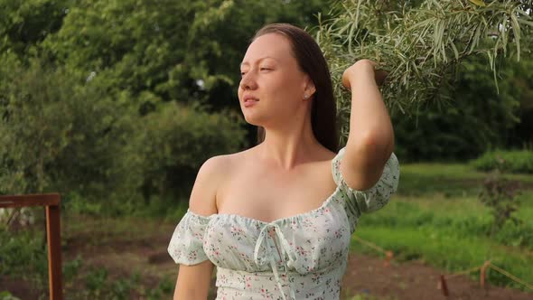 Woman Touching Tree Branches in Garden