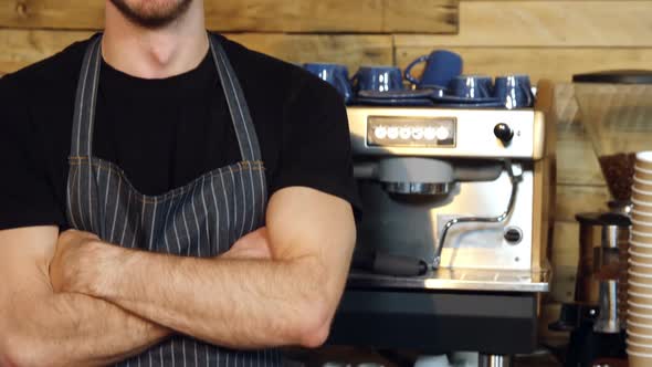 Portrait of smiling waiter standing with arms crossed