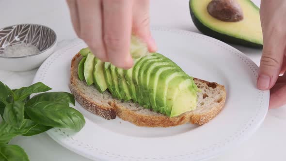 Cooking avocado toast. Sliced avocado on bread with lime and salt.