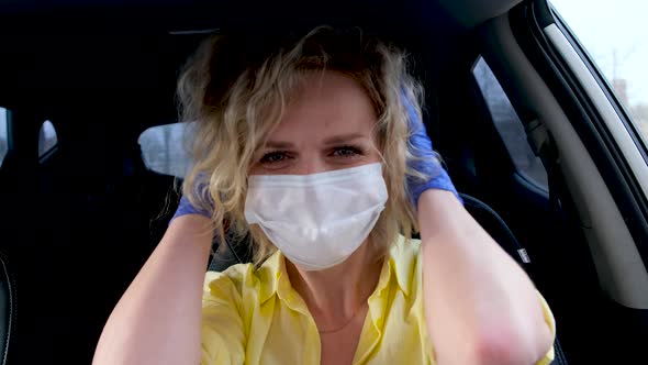 Curly Blonde Girl Driver in Summer Wear and Medical Mask and Protective Gloves Straightens Her Hair