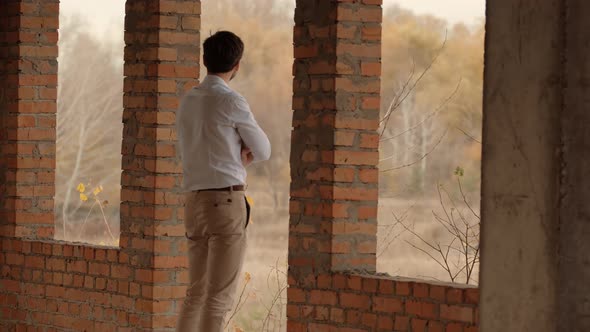 Businessman In White Shirt Standing In Unfinished House And Thinking. Man Watching To Horizon.