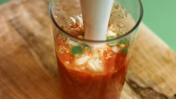 Pouring diced tomatoes from an open can into hand blender glass. Process of making salsa