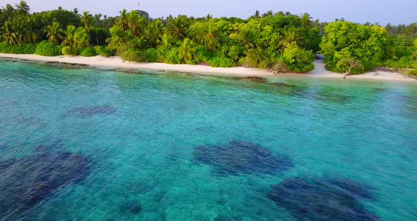 Wide fly over tourism shot of a white sand paradise beach and blue sea background in vibrant