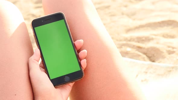 NICE, FRANCE - JULY 2017 Caucasian female holds green screen display phone on the beach