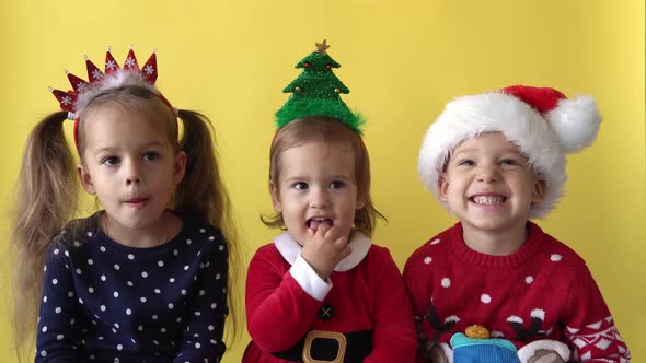 Emotion Cute Happy Cheerful 3 Siblings Friends Baby Girl And Boy in Santa Suit Looking On Camera At