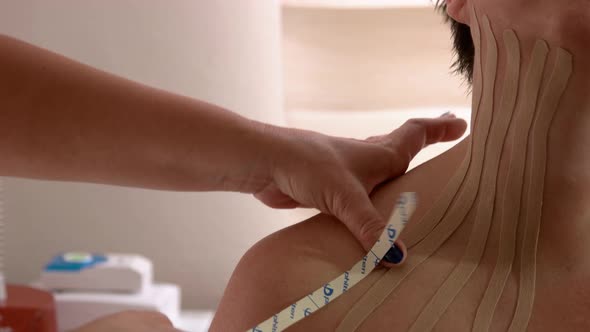 Physical Therapist Placing Kinesio Tape on Patients Neck