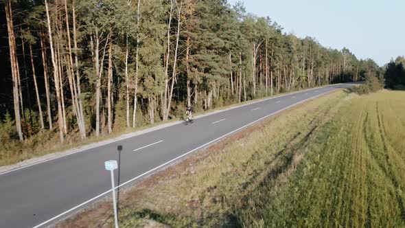 Drone Shot of Cyclist Riding a Road Bike on a Highway Near Field in Summer