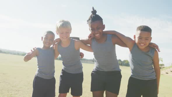 Video of happy diverse boys walking on grass and holding arms