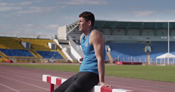 Sweaty Sportsman Resting Near Hurdle