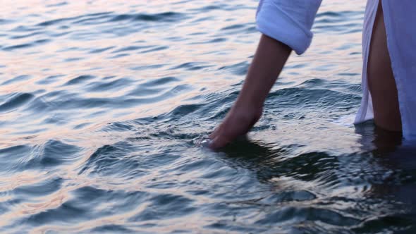 Women in white posing at sunrise. The girl bathes in the water during the sunrise on a warm summer