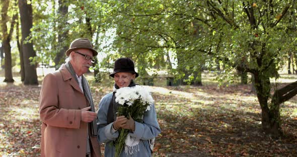 Elderly Woman with Bouquet of Flowers Having Pleasant Talk with Lovely Cavalier