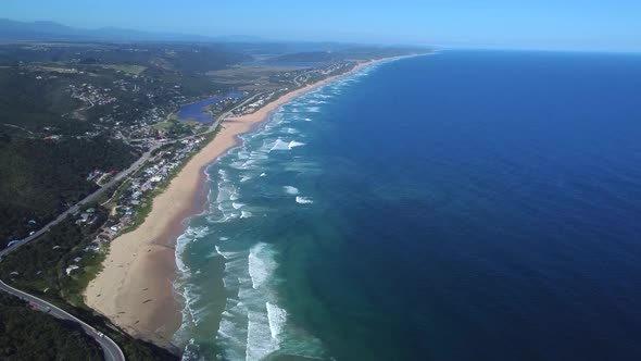 Drone shot of Wilderness beach in South Africa - drone is circling, facing ocean, beach, hills and t