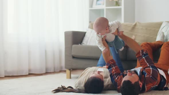 Happy Mother and Father Playing with Baby at Home