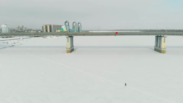 Long Bridge with Driving Automobiles Over Frozen River