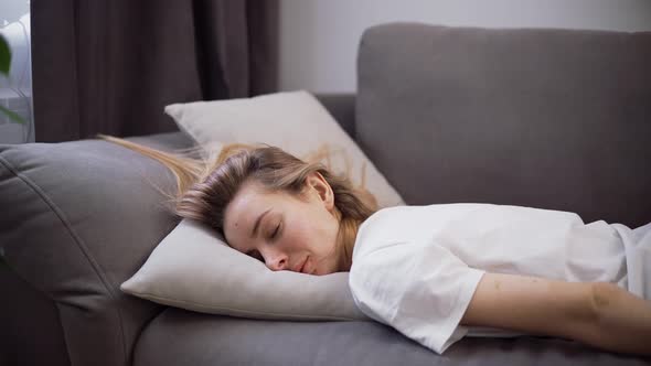 Exhausted or Bored Young Sleepy Woman Falls Down on Sofa