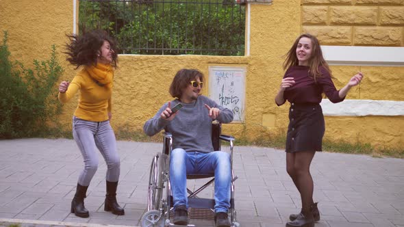 man using wheelchair dances with his friends - fun, disability