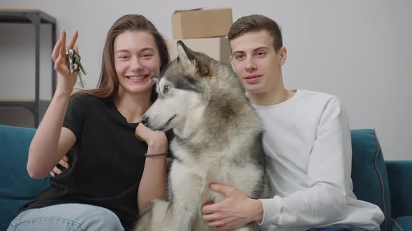 Happy Young Family Together with a Dog are Sitting on the Couch in a New Apartment