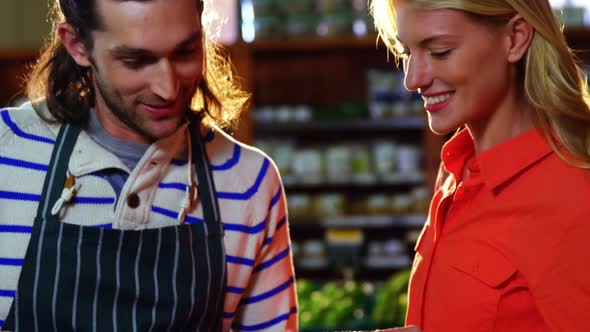 Male staff assisting woman in selecting fresh vegetables