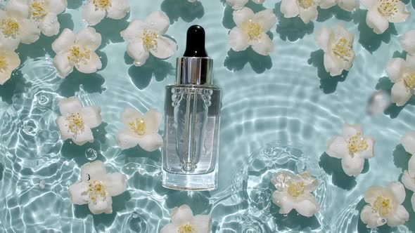 Cosmetic Bottle Vial and Jasmine Petals Flowers on Water Surface with Drops