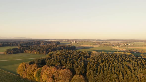 Aerial clip of the Bavarian plain, with a forest in the foreground and a road, with cars moving, in