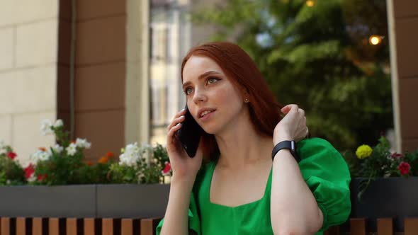 Closeup Face of Cheerful Young Woman Talking on Smartphone and Looking Away Sitting at Table in