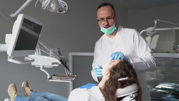 Denist examining teeth of a woman and explaining treatment