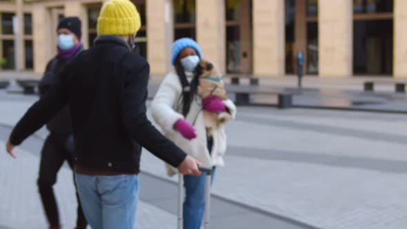 Multiethnic Couple Wearing Safety Mask Meeting After Long Time Hugging Near Airport with Pug Dog