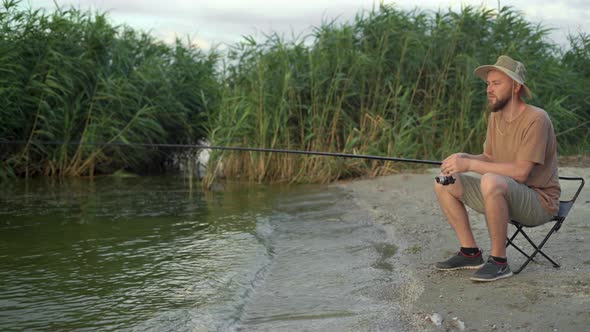 a Man Fisherman at Dawn on the Lake Catching Fish with a Bait